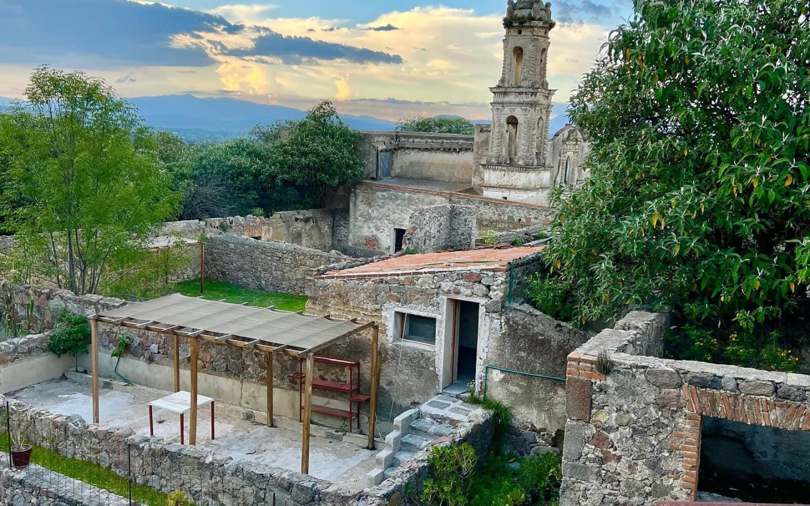 Descubre la majestuosidad de la Hacienda Santa Bárbara en esta impresionante fotografía que captura su torre emblemática, contrastando con un cielo azul vibrante y exuberante vegetación verde. ¡Explora la historia y la belleza de este lugar único!